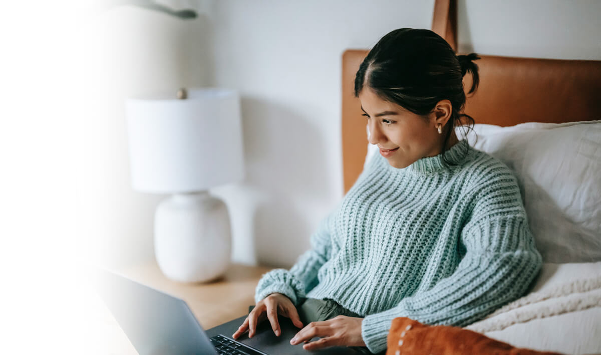 Woman sitting in bed in front of laptop